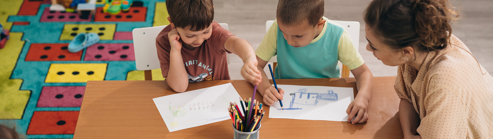 Teacher watching two students draw in class